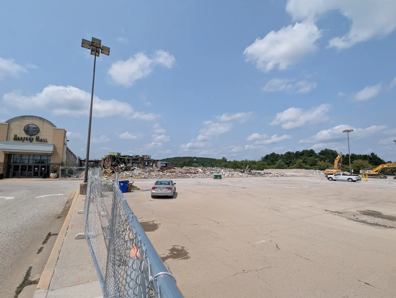 East-side view across the cleared former Macy's footprint at Harford Mall, with the retained mall entrance at left