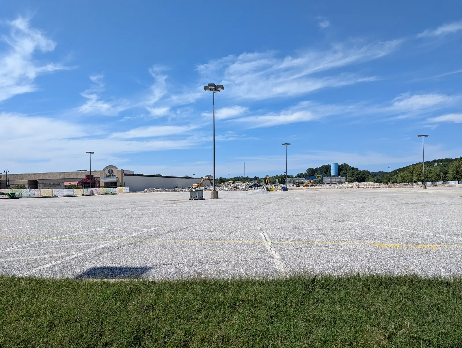 East-side view across the former Macy's footprint, now mostly open ground and rubble, with the retained Harford Mall at left