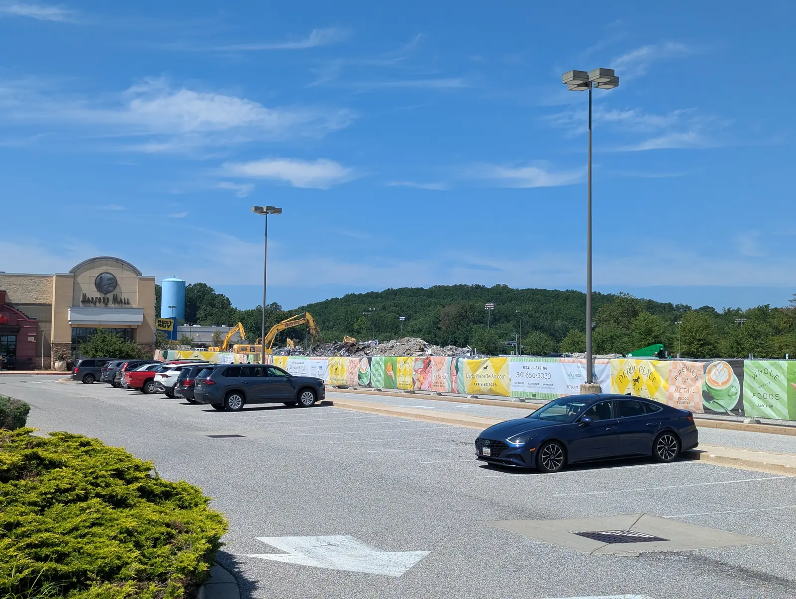 Southeast view of the open Harford Mall entrance, Derby Place construction fence, demolition equipment, and rubble